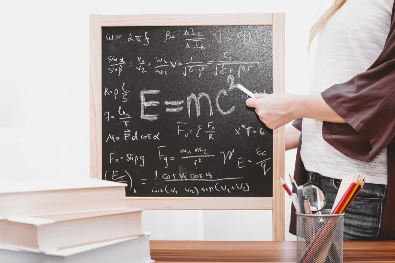 A teacher explaining physics formulas on a blackboard at Taj Pinnacle Institute